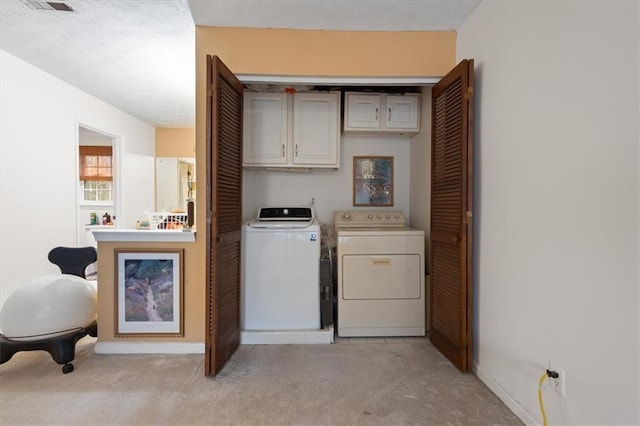 laundry area featuring separate washer and dryer, light carpet, and a textured ceiling