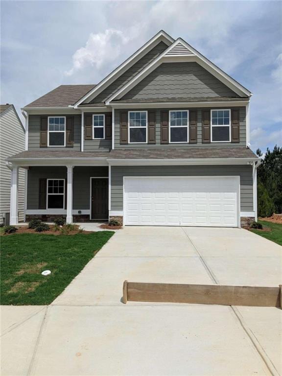 craftsman inspired home with covered porch, a garage, and a front yard