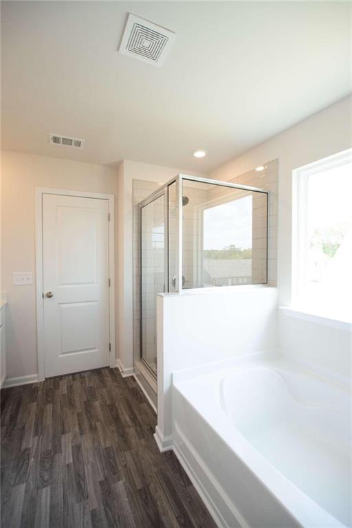 bathroom with vanity, hardwood / wood-style flooring, and plus walk in shower