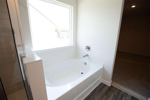 bathroom with shower with separate bathtub and wood-type flooring