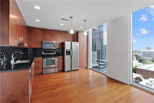 kitchen featuring appliances with stainless steel finishes, decorative light fixtures, a wealth of natural light, and sink