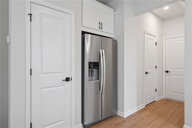 kitchen with white cabinets, stainless steel refrigerator with ice dispenser, and light hardwood / wood-style floors