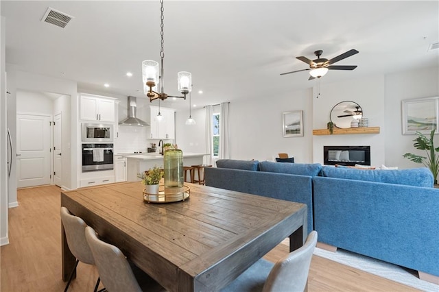 dining area with light hardwood / wood-style flooring and ceiling fan with notable chandelier