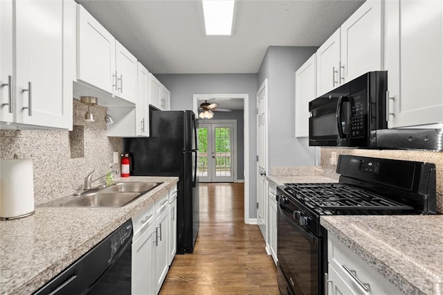 kitchen with wood finished floors, a sink, white cabinetry, black appliances, and light countertops