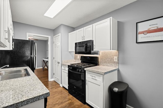kitchen with baseboards, a sink, white cabinetry, backsplash, and black appliances