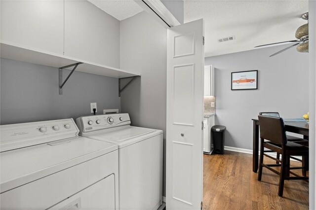 laundry room with visible vents, ceiling fan, wood finished floors, laundry area, and washer and clothes dryer