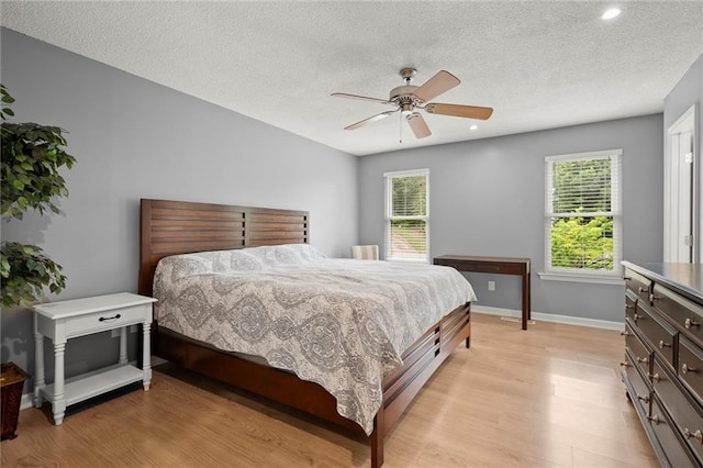 bedroom featuring multiple windows, light wood-style flooring, and a textured ceiling
