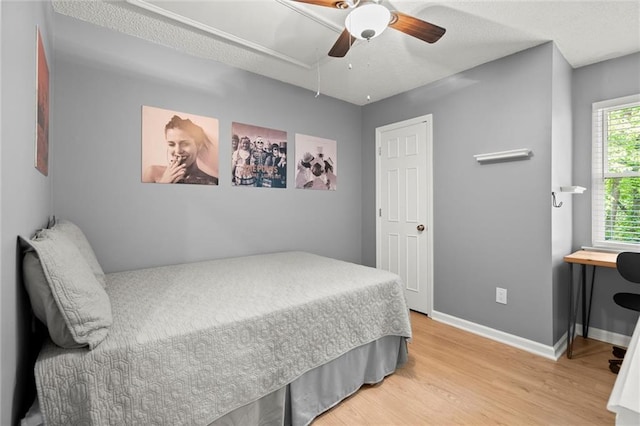 bedroom with attic access, baseboards, a ceiling fan, and wood finished floors