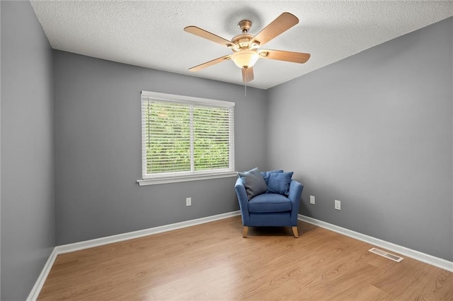 unfurnished room featuring wood finished floors, a textured ceiling, visible vents, ceiling fan, and baseboards