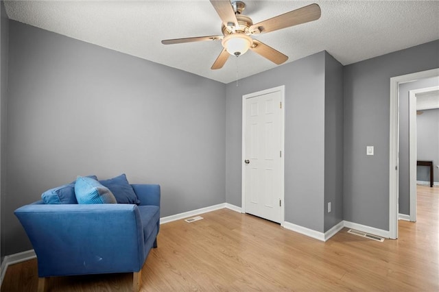 sitting room with baseboards, light wood-type flooring, and visible vents