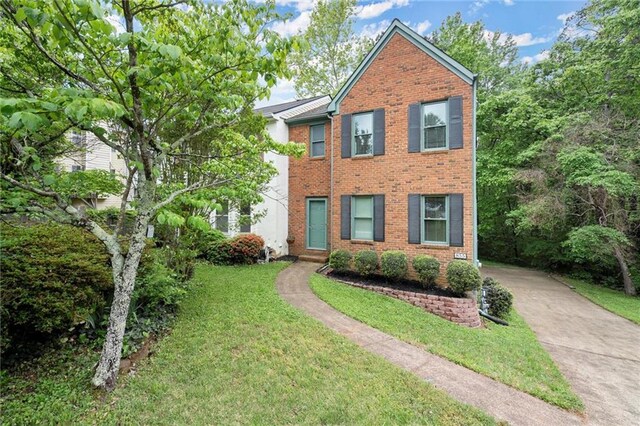 view of front of home featuring concrete driveway, brick siding, and a front yard