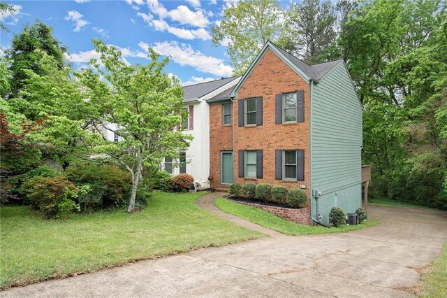 view of front of house with concrete driveway, brick siding, and a front yard