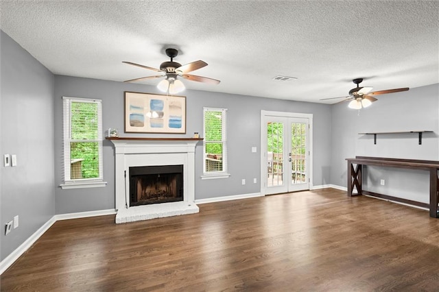 unfurnished living room with a ceiling fan, a textured ceiling, visible vents, and a fireplace with raised hearth