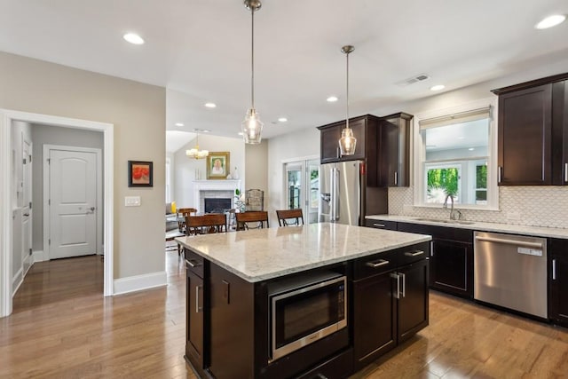 kitchen with appliances with stainless steel finishes, a sink, tasteful backsplash, light wood-style floors, and recessed lighting