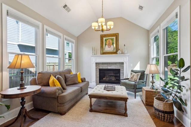 living room with vaulted ceiling, a chandelier, a fireplace, and wood finished floors