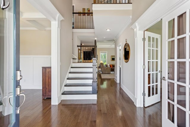 entryway with crown molding, wood finished floors, stairs, a decorative wall, and french doors