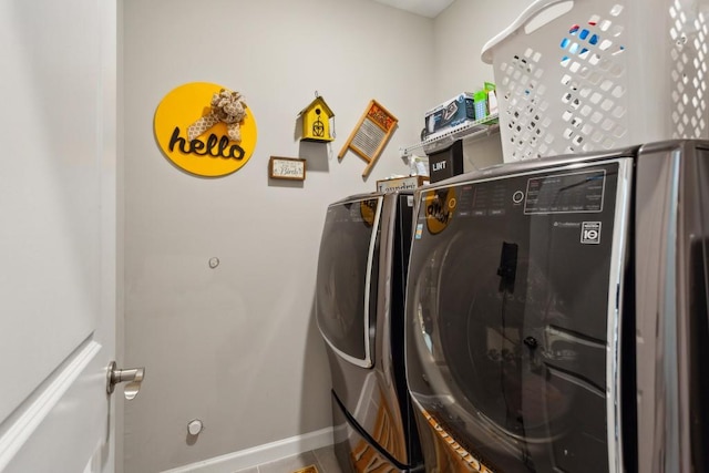 clothes washing area with washer and clothes dryer and baseboards