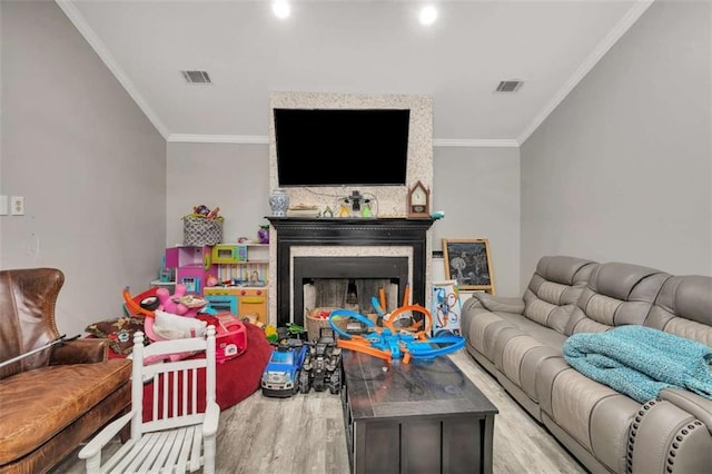 living room featuring light wood-type flooring, a large fireplace, and crown molding