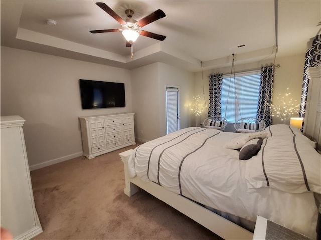 bedroom with carpet floors, ceiling fan, and a tray ceiling