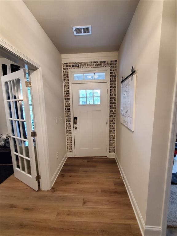 doorway to outside featuring wood-type flooring and brick wall