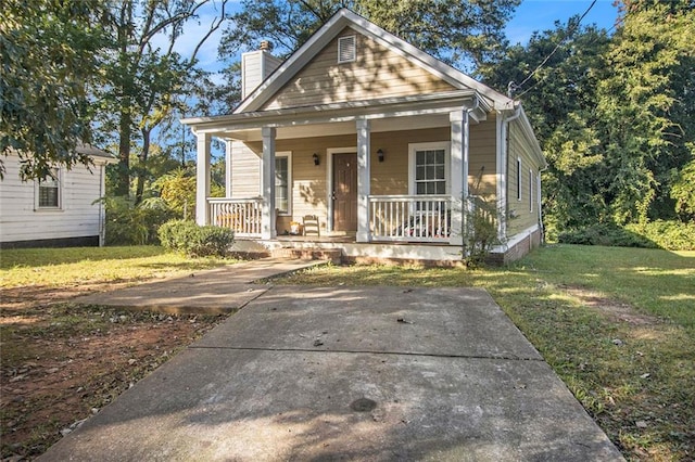 bungalow-style home featuring covered porch and a front yard