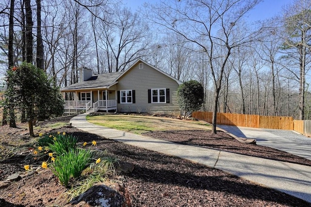 view of front facade featuring a porch, a chimney, and fence