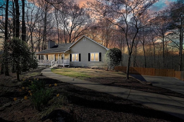 view of front of property with a porch, a chimney, and fence