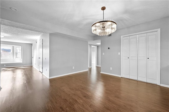 interior space featuring dark wood-type flooring, a chandelier, and a textured ceiling