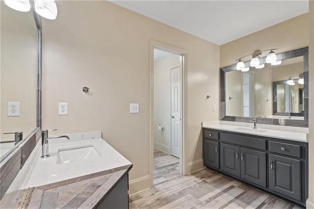 full bathroom with two vanities, a sink, and wood finished floors