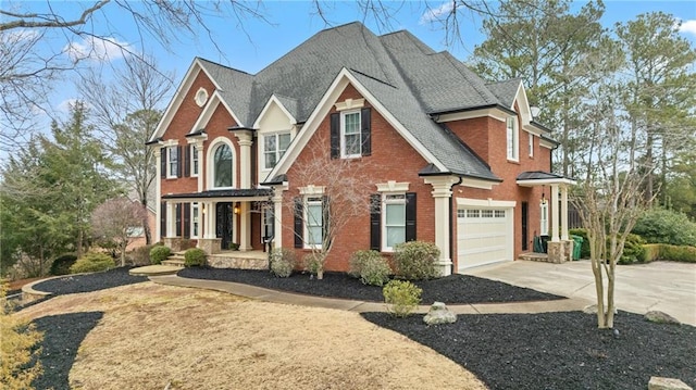 view of front of house with a garage, concrete driveway, brick siding, and roof with shingles