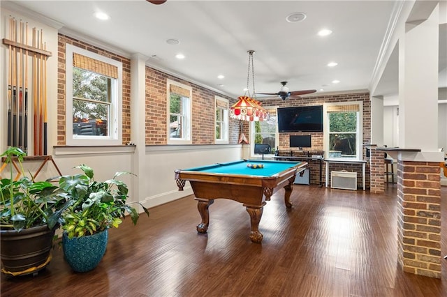 playroom featuring dark wood-style floors, brick wall, ornamental molding, and ceiling fan