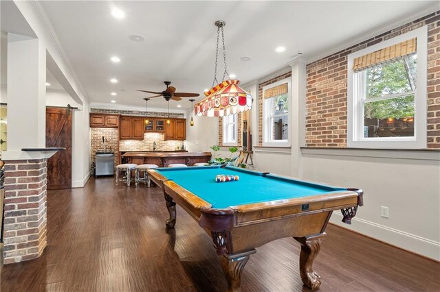 recreation room with a barn door, baseboards, dark wood-style flooring, crown molding, and recessed lighting