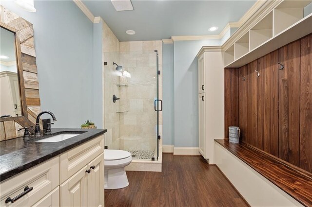 full bathroom featuring toilet, wood finished floors, crown molding, vanity, and a shower stall