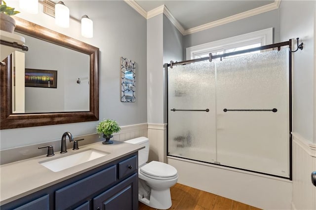 bathroom featuring a wainscoted wall, toilet, ornamental molding, enclosed tub / shower combo, and wood finished floors