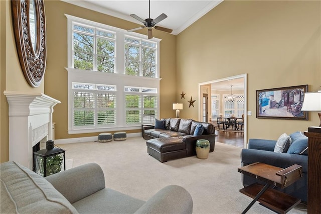 carpeted living area with a fireplace, ornamental molding, high vaulted ceiling, baseboards, and ceiling fan with notable chandelier