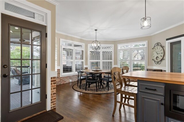 dining area featuring a chandelier, brick wall, ornamental molding, and dark wood-type flooring