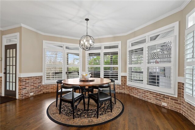 dining space with dark wood-type flooring, crown molding, a notable chandelier, and brick wall