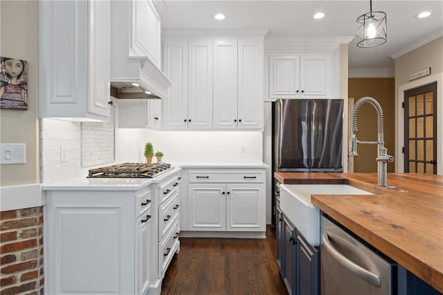 kitchen with butcher block countertops, white cabinetry, appliances with stainless steel finishes, blue cabinetry, and decorative light fixtures