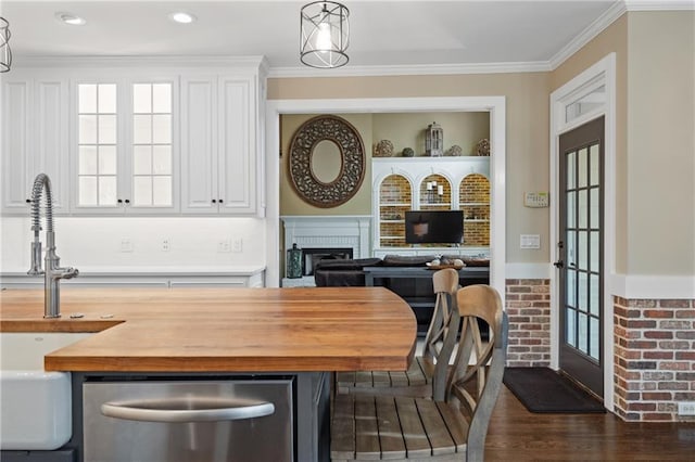 dining space with built in shelves, dark wood-style flooring, a fireplace, and crown molding