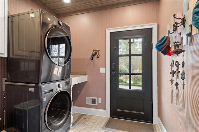 washroom featuring laundry area, a wealth of natural light, light wood-style flooring, and stacked washer / drying machine