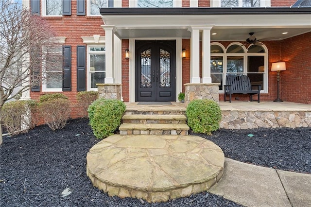 doorway to property featuring a porch, french doors, and brick siding