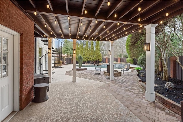 view of patio with a pool with connected hot tub, stairs, a fire pit, and fence