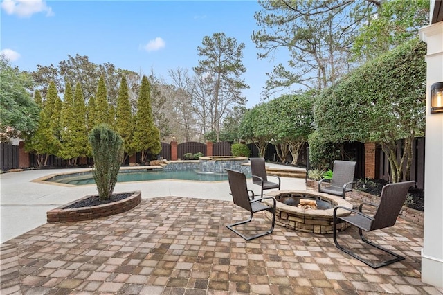 view of patio featuring an outdoor fire pit, a pool with connected hot tub, and a fenced backyard