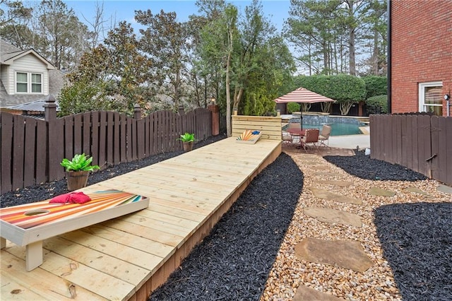 view of yard featuring a deck, a patio area, a fenced backyard, and a fenced in pool