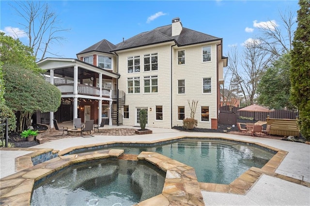 back of house with a sunroom, a chimney, stairway, fence, and a patio area