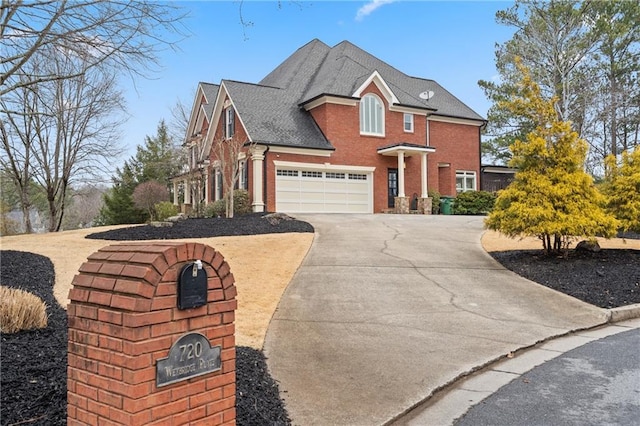 traditional home with a garage, driveway, brick siding, and a shingled roof