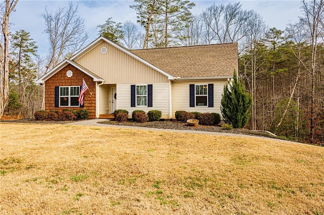 ranch-style home featuring a shingled roof and a front yard