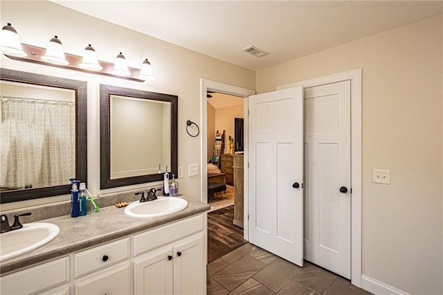 ensuite bathroom featuring double vanity, visible vents, a sink, and ensuite bathroom