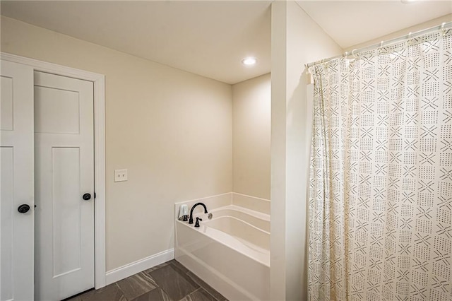 bathroom featuring baseboards, a bath, and a shower with shower curtain