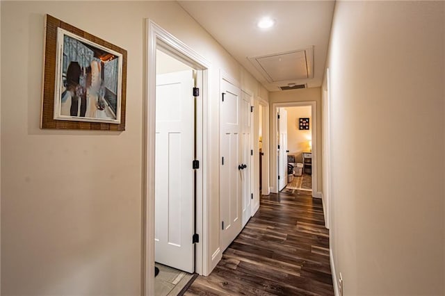 corridor featuring dark wood-type flooring, recessed lighting, attic access, and baseboards